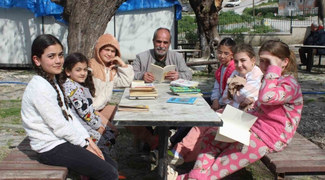 Eline kitabı alan muhtar, çocuklara örnek olmak için birlikte kitap okuyor